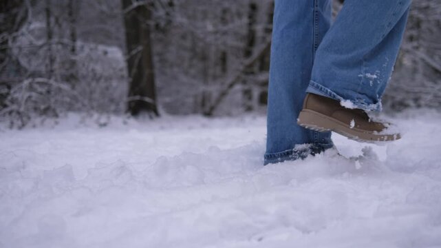 Close-up of a person walking through deep fresh snow in winter boots. Winter outdoor walk in a snowy forest, showing movement through soft snow.