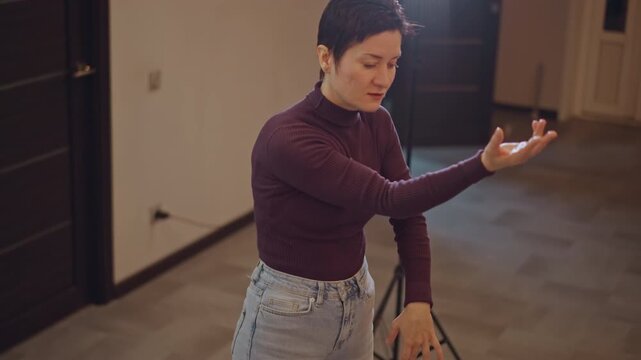 Music coach instructing proper breathing and posture in studio setting. Professional female tutor teaching breathing and hand movements with corrective guidance in welllit studio environment