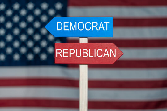 US political choice Democrat and Republican signposts. Wooden sign Democrat and Republican arrows pointing in opposite directions on US flag background symbolizing political choices and division