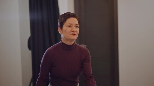 Asian vocal teacher in small studio guiding private lesson, conversational tone with calm gestures, door and curtain backdrop, demonstrating pitch with hand, handheld vocal ball, attentive feedback,