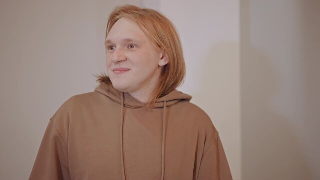 Redhead student practicing lines with apple. Hoodieclad performer in neutral room, delivering animated monologue with intense facial expressions, raw youthful energy, visible nerves and charisma,