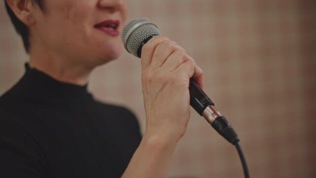 Solo vocal practice in cozy studio, teacher led warmup with handheld microphone, plaid backdrop, expressive phrasing, posture coaching, confidence training and performance rehearsal
