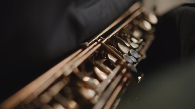 Lowangle saxophone keys during warmup, technician or roadie prepping instrument before gig, dark moody backdrop with spotlight glint, brass lacquer and pearl pads in crisp focus, cinematic shallow
