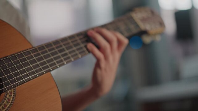 Closeup fretting hand on guitar neck, advanced student executes barre chords and scale runs with precise fingering, stretching and speed work under coaching in studio, focused preparation for audition