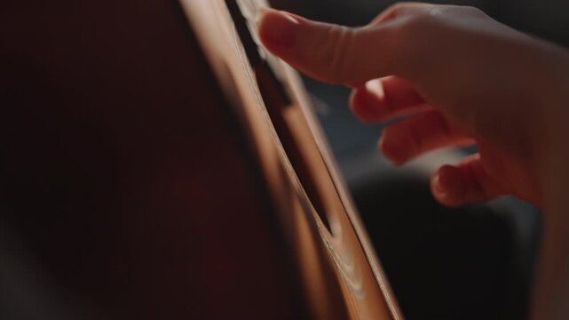 Fingerstyle plucking close up hand on strings, delicate nail strokes creating melody lines, detailed view of fretboard and hand movement, intimate practice session with warm light and soft focus