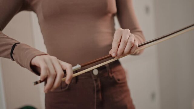 White coach demonstrating precise bow grip adjustment in studio, closeup hands showing fingertip placement and wrist alignment, thoughtful correction, calm teaching tone, emphasis on control and sound