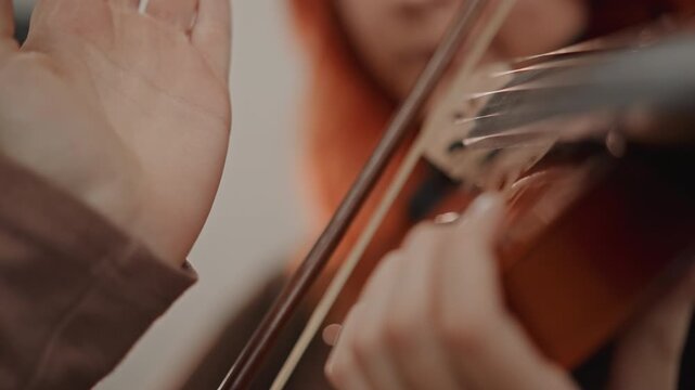 Closeup bow technique coaching white teacher adjusts students righthand grip on violin bow, warm studio lighting, focused hands, careful posture and steady guidance during private lesson