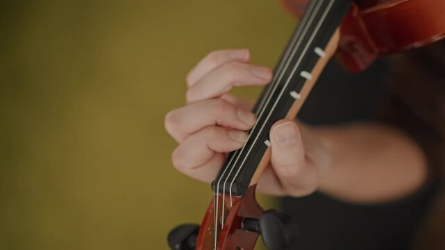 Violin fingerboard close up teacher guiding fingers, student receives gentle fingering instruction, warm studio light, teacher adjusts hand position, focused practice on intonation and finger