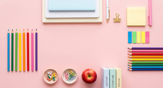 Back to school flat lay of colorful pencils, notebooks and an apple on a pastel background, top view copy space
