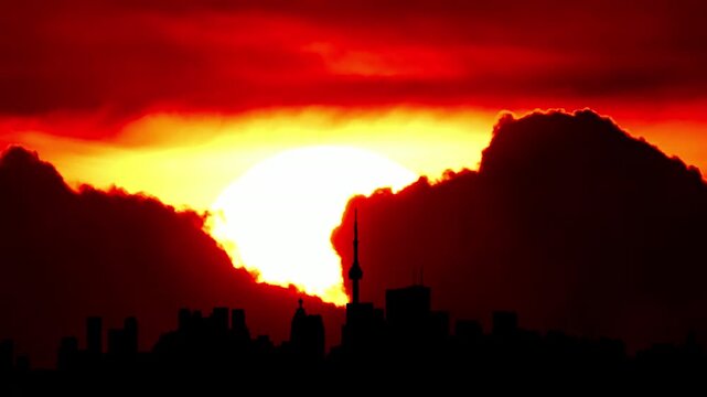 City skyline silhouette hot cinematic sun set, downtown cityscape with large sun disk sunset light. Artistic effects. Epic hot summer sky with buildings and yellow sun disk. Heat wave warning.