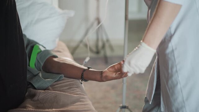 Doctor inserting iv into patient arm, white coat gloved hands placing cannula, green tourniquet visible, clinical bedside scene, tubing and clamp in frame, concentrated technique and immediate