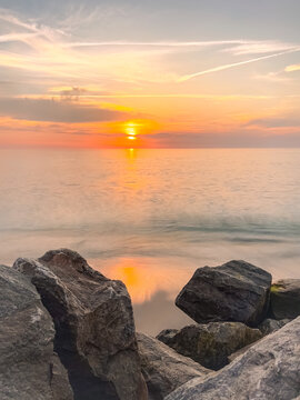 Golden ocean sunset over rocky beach shoreline view