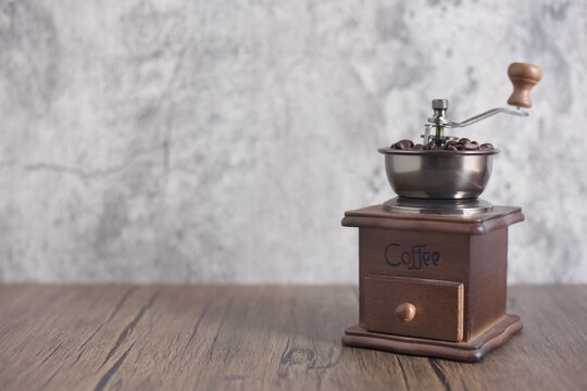 Manual coffee grinder with coffee beans on modern background