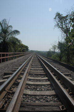 Low angle view of straight railway tracks stretching into the horizon over a bridge