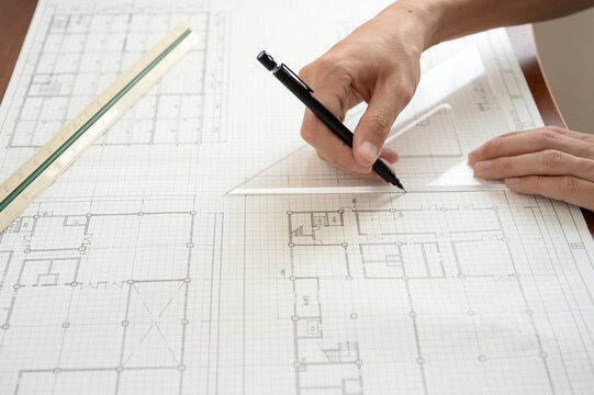 Architect drawing on architectural blueprint with ruler and pen
定規とペンを使って建築図面に線を引く建築士の手元