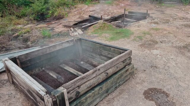 Steaming wooden geothermal cooking boxes in Tokaanu, New Zealand, used for natural thermal food preparation.