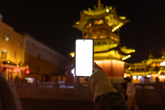 Hand holding smartphone displaying blank screen in Datong, China night
