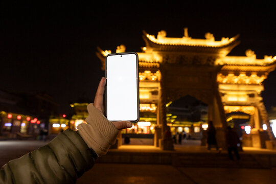 Hand holding smartphone capturing Datong China night scene