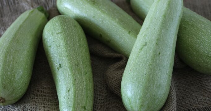 Fresh zucchinis on wooden table, closeup. Camera moving left