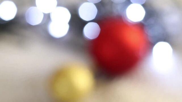 Una toma de cerca de bolas de navidad de varios colores con luces de navidad con desenfoque en un fondo negro. 