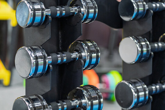 Electroplated dumbbells neatly placed on gym equipment rack