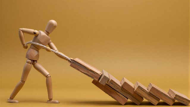 Wooden figure pulls dominoes, symbolizing effort to prevent chain reaction.
