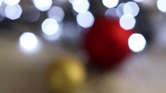 Una toma de cerca de bolas de navidad de varios colores con luces de navidad con desenfoque en un fondo negro. 