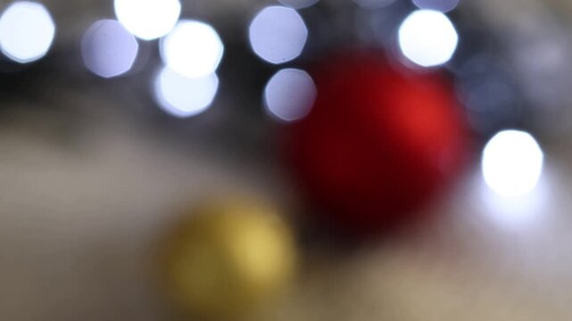 Una toma de cerca de bolas de navidad de varios colores con luces de navidad con desenfoque en un fondo negro. 