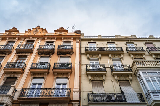 Upward view of residential building facades in Ciutat Vella in valencia, spain, with decorative balconies and historic architectural details typical of the city's central housing stock and real estate
