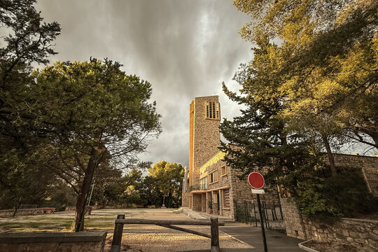 Chapelle Notre-Dame de Consolation on Costebelle hill in Hyeres, France. The modern stone chapel, designed by Raymond Vaillant and built in the 1950s, is framed by Mediterranean trees.