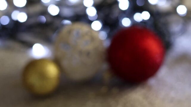 Una toma de cerca de bolas de navidad de varios colores con luces de navidad con desenfoque en un fondo negro. Bokeh