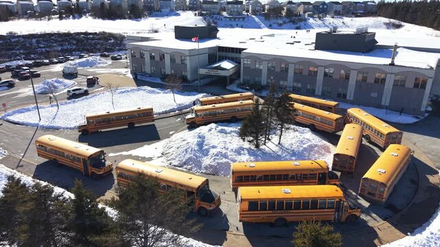 Winter view of yellow school buses parked near a school in Halifax, Nova Scotia, showcasing the beauty of snow-covered surroundings