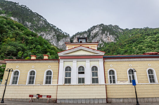 Main facade of the Cerna balnear treatment center in Baile Herculane, Romania, part of the spa and thermal resort, with arched windows and a mountain landscape rising directly behind the building.