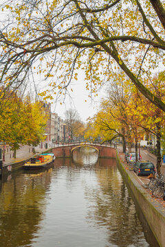 Historic arch bridge over autumn canal in Amsterdam, vertical travel background with copy space