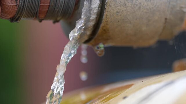 Water pipe leak drip flow faucet plumbing metal closeup, rusty outdoor spout stream from corroded fitting, droplet splash wet surface, maintenance waste repair need urgent fix