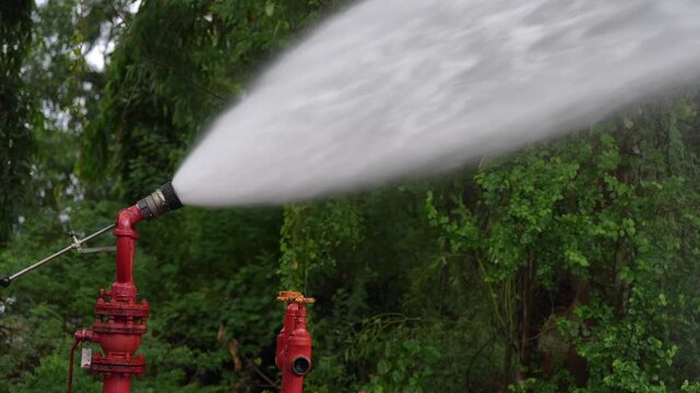 Fire hydrant water spray firefighting fire monitor emergency safety forest fire prevention water jet fire suppression, red hydrant valve pressurized stream mist during drill training for fire control