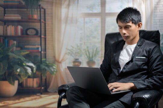 Young Man Working on Laptop in Cozy Modern Living Room Setting