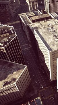 A busy city area with tall buildings and streets. Cars drive on the road below. The image captures the layout of the blocks from a high angle.
