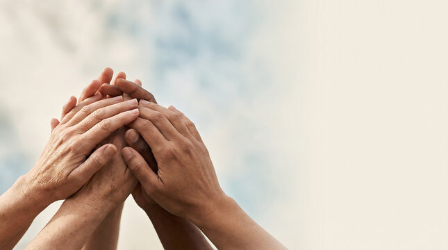 Human rights day concept, diverse group of hands clasped together reaching up against sky copy space