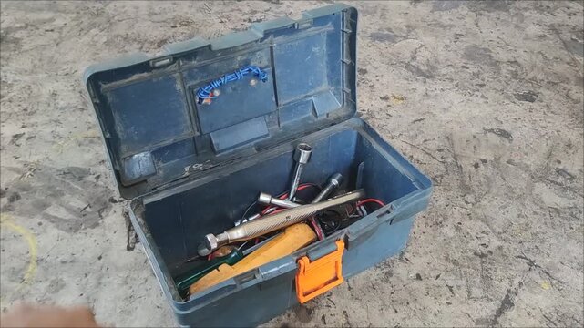 a hand opening a toolbox containing tools