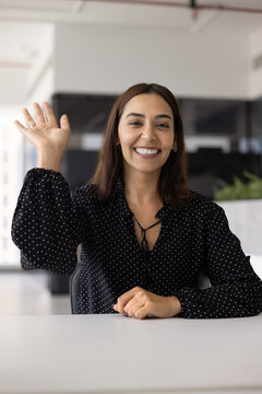 Profile picture of smiling Arabian young 35s woman start video call seated in modern office, greeting corporate client, finalize remote negotiations. Virtual meeting event, digital communication, tech
