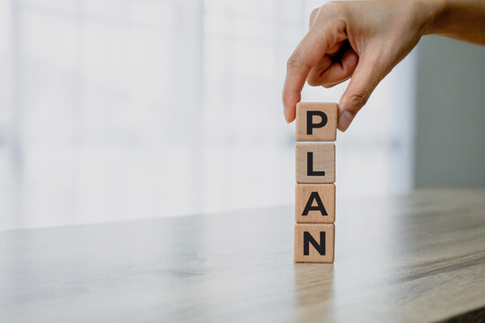 Close-up of a hand placing wooden letter blocks spelling PLAN. Business planning, strategy, goal setting, project management and growth concept with copy space.
