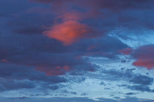 Dramatic evening sky with vibrant clouds in shades of blue and orange, showcasing a stunning natural landscape at dusk with soft light and atmospheric depth