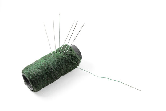Green thread and needles isolated white background 