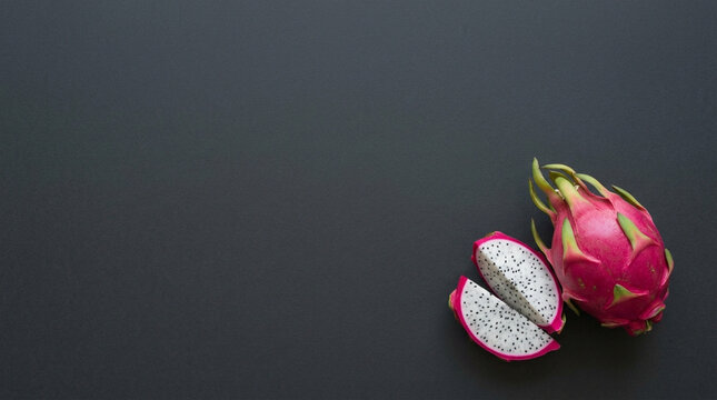 Vibrant pink dragon fruit, whole and sliced, showcasing its exotic beauty and unique texture on a dark background with copy space.