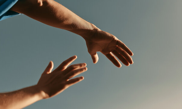 a close up shot of a hand in the foreground reaching up towards a hand extending down from the upper left.
