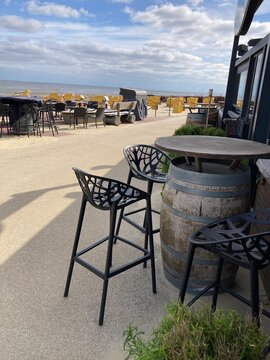 Idyllischer Sitzplatz an Restaurant an der Strandpromenade in Cuxhaven an der Nordsee mit 
Blick auf Meer und Strand