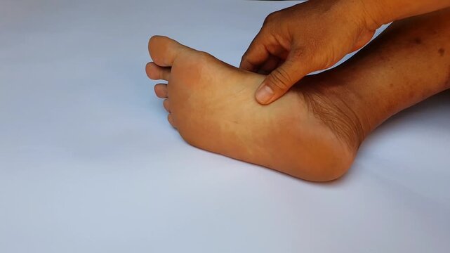Self foot massage pressing reflexology acupressure points on the sole for pain relief and relaxation.