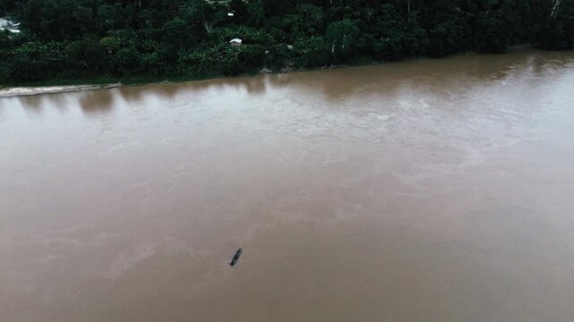Drone View of Boat on Wide Brown Amazon River in Ecuador, Dense Rainforest Banks, Remote Jungle Transport and Tropical South American Waterway Scene