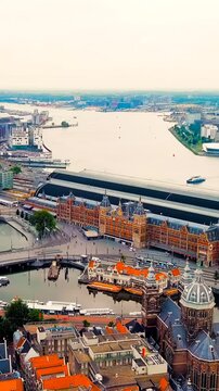 Vertical video. Amsterdam, Netherlands. Amsterdam Central Station. Amsterdam Centraal - The largest train station in the city, built in 1889. Bay IJ (Amsterdam). Drone footage, Point of interest. Ric